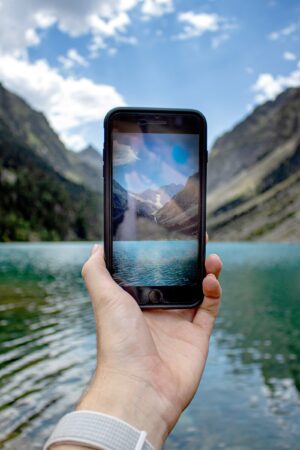 Image of a hand holding a phone with mountains and water in the background.