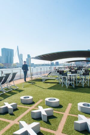 The top deck of a cruise ship with fake green grass and a tic-tack-toe board in the foreground.