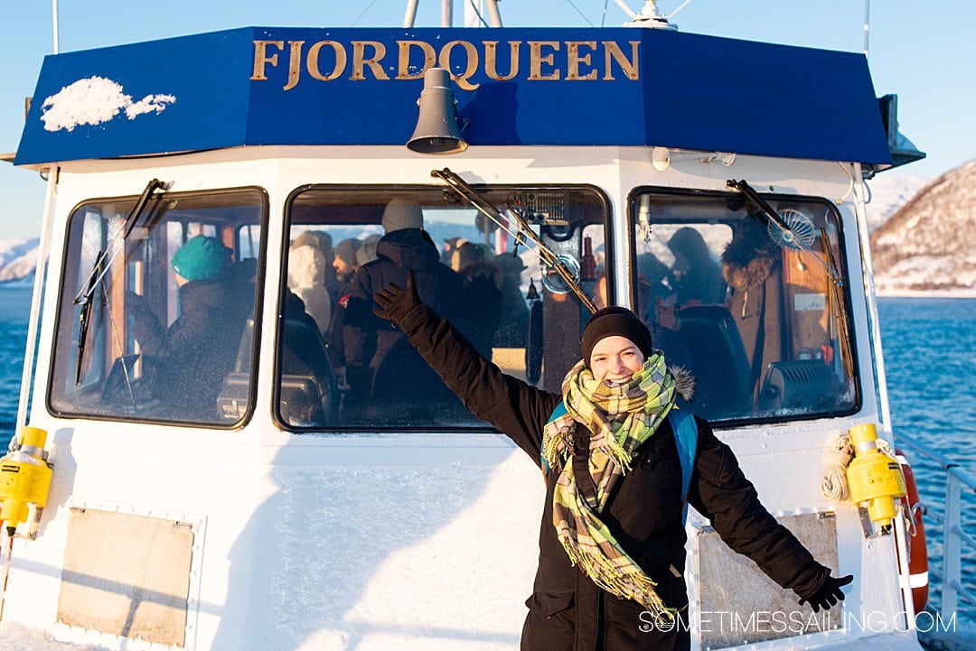 A women in front of the windshield of a boat with "FjordQueen" letters above.