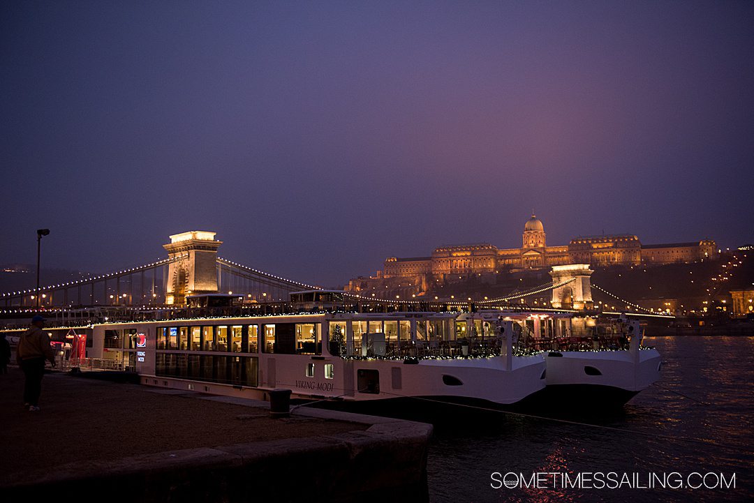 Bridge and castle in Budapest during night time, illuminated by lights for a Christmas Markets River Cruise post.