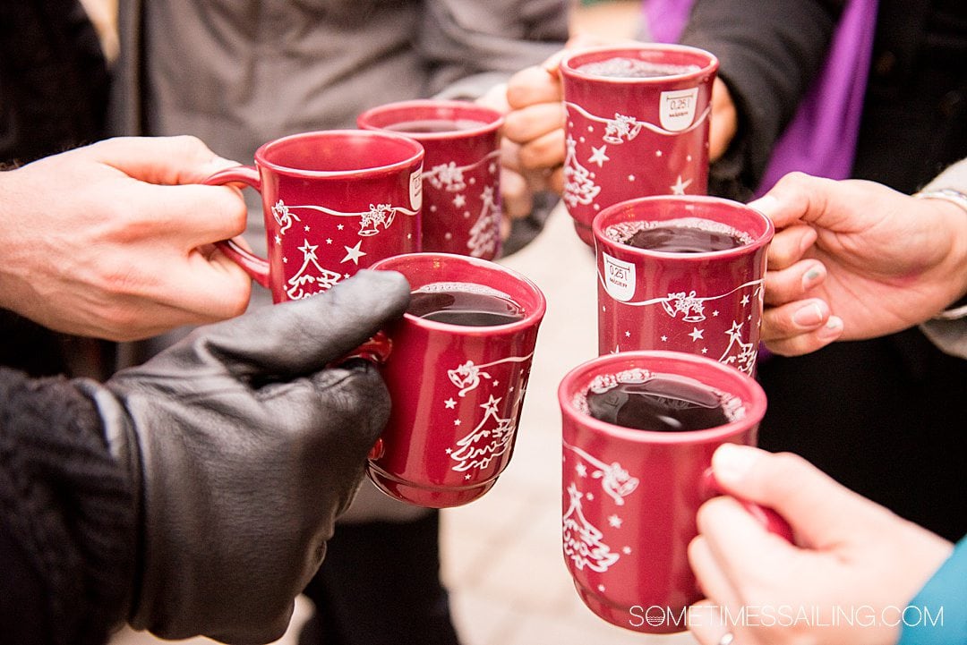 Hands holding red mugs with red wine in them at a Christmas Market in Vienna, Austria.