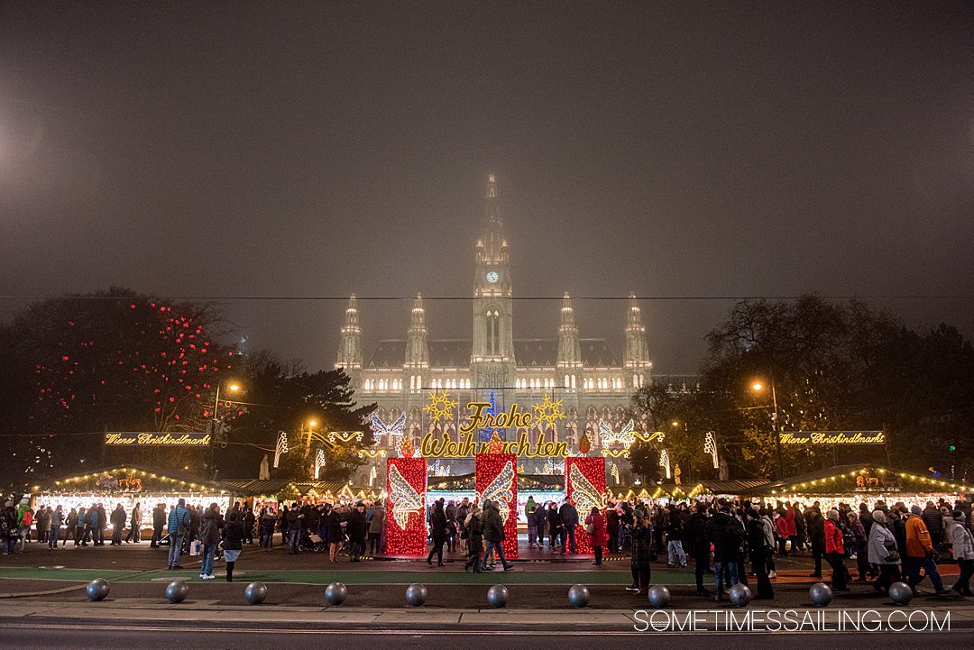 Misty night sky with a European building in the distance and holiday sign illuminated by Christmas lights in Vienna, Austria.