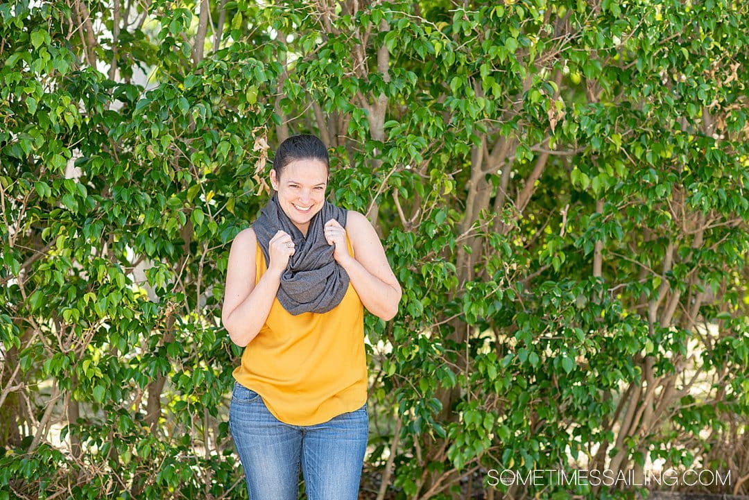 Woman in a grey wrap scarf that converts from to a blanket for best cruise gifts.