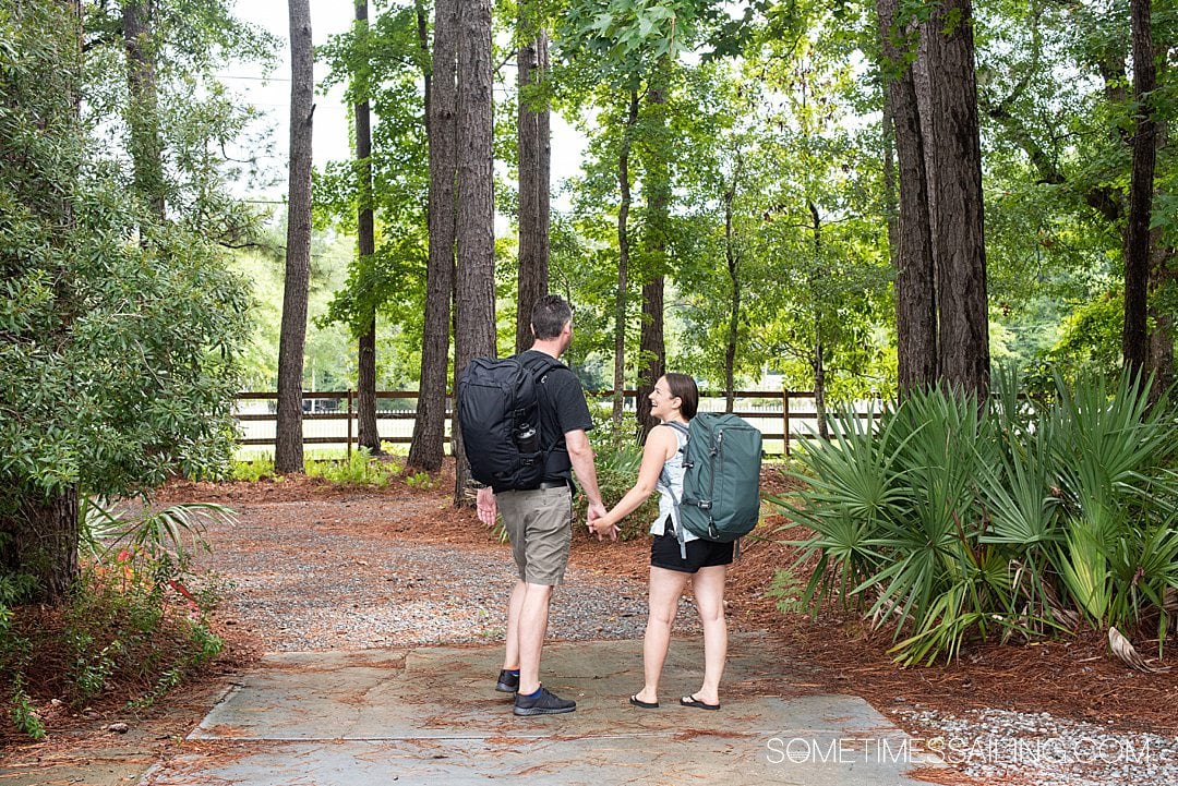 Man and a woman walking away with a black and green backpack on, respectively. 