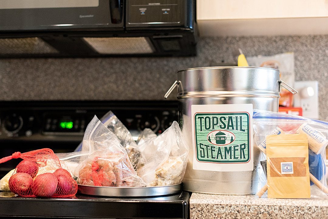 Contents of a seafood steamer pot for a Topsail Steamer review laid out on a counter with seafood, corn and potatoes inside in plastic bags.