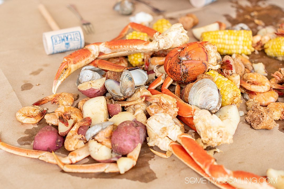 A bed of seafood and vegetables, including corn and potatoes, clams shrimp and crab legs.