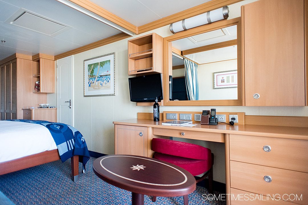 Interior of a cabin on the Disney Dream cruise line ship with a red chair and natural wood colored cabinets.