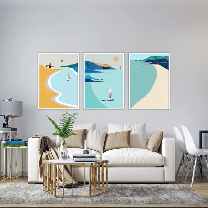 NordicOcean digital art on Etsy. Three paintings hang about a living room scene with a couch and table. 