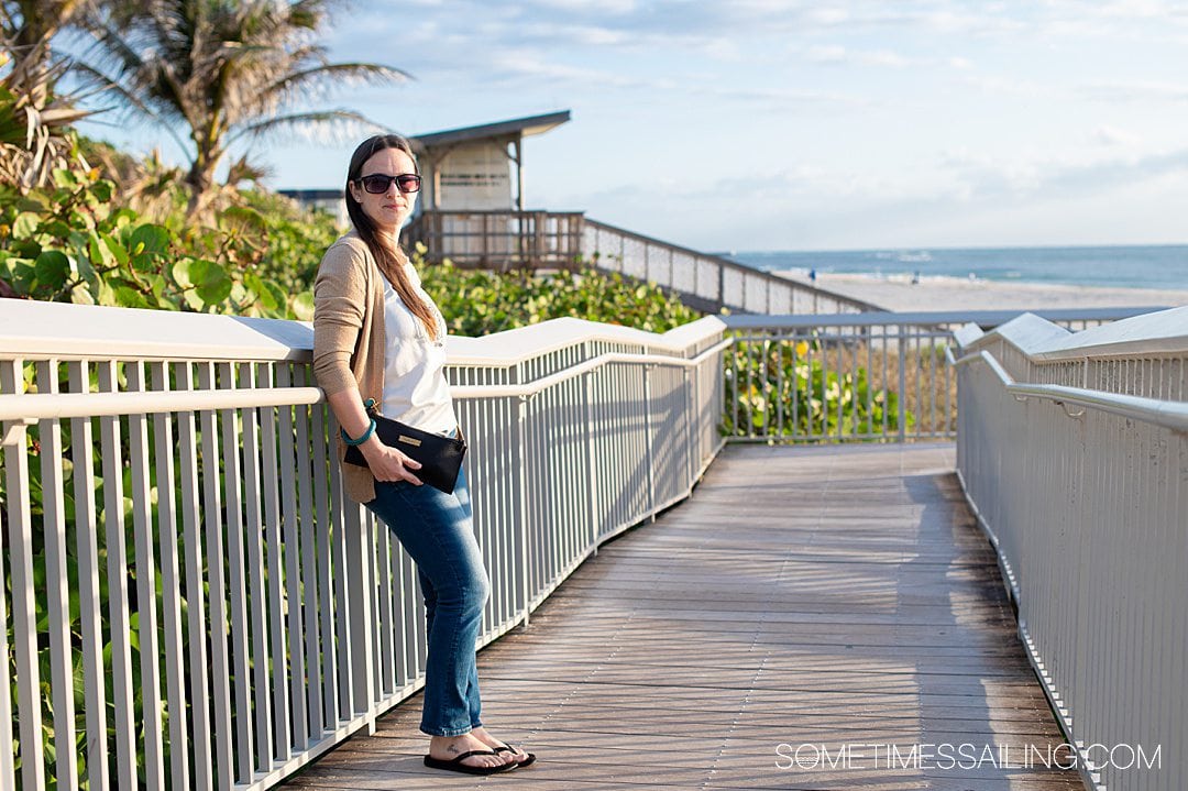 Woman holding a black and teal clutch with a seaweed nautical bracelet on.