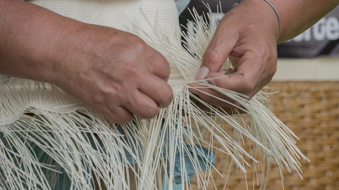 Hands crafting a toquilla palm fiber hat in Ecuador.