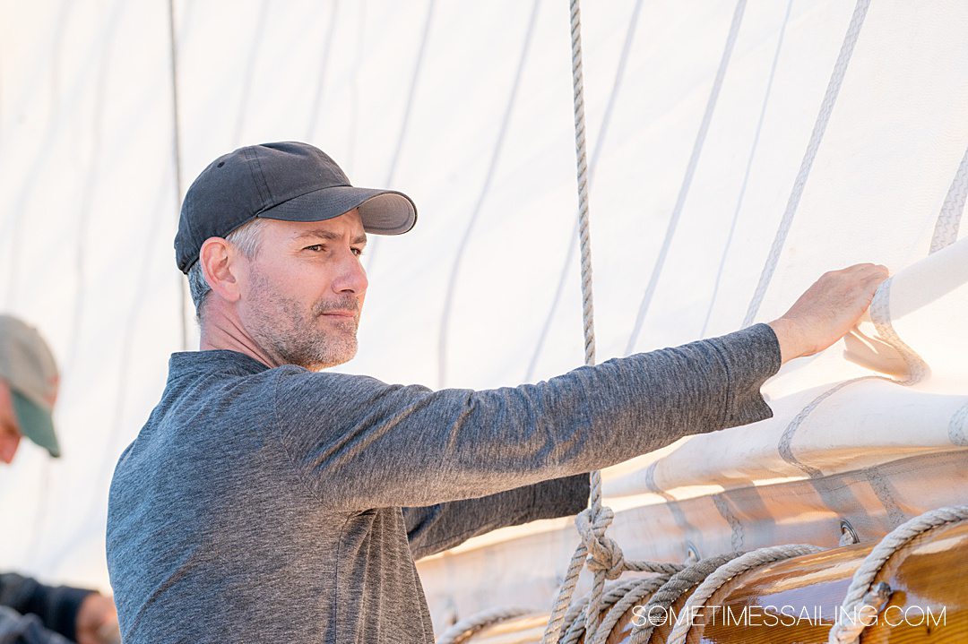 Man folding the sails on a Maine Windjammer Cruise sailing experience.