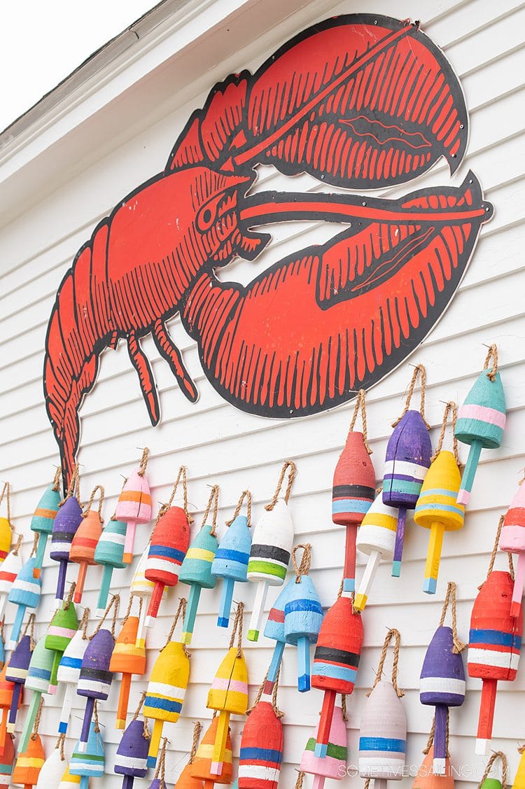 Colorful wooden buoys on a white wall with a red lobster cutout in Stonington, Maine.