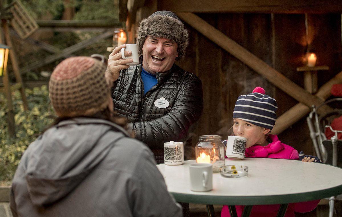 Adventure Guide for Adventures by Disney river cruise with a man in a furry hat with a Disney name tag next to a child at the Christmas Markets in Europe.