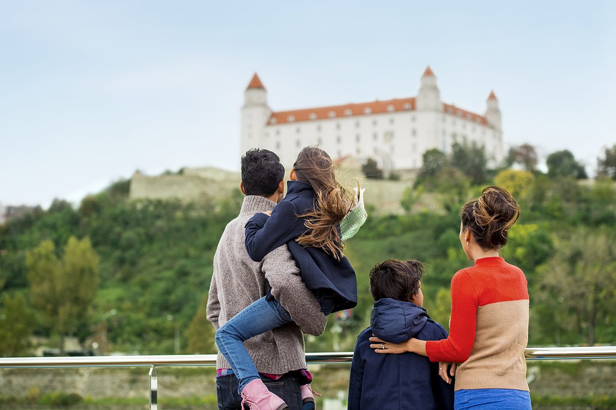 Family looking at a castle on a hill from a river cruise ship.