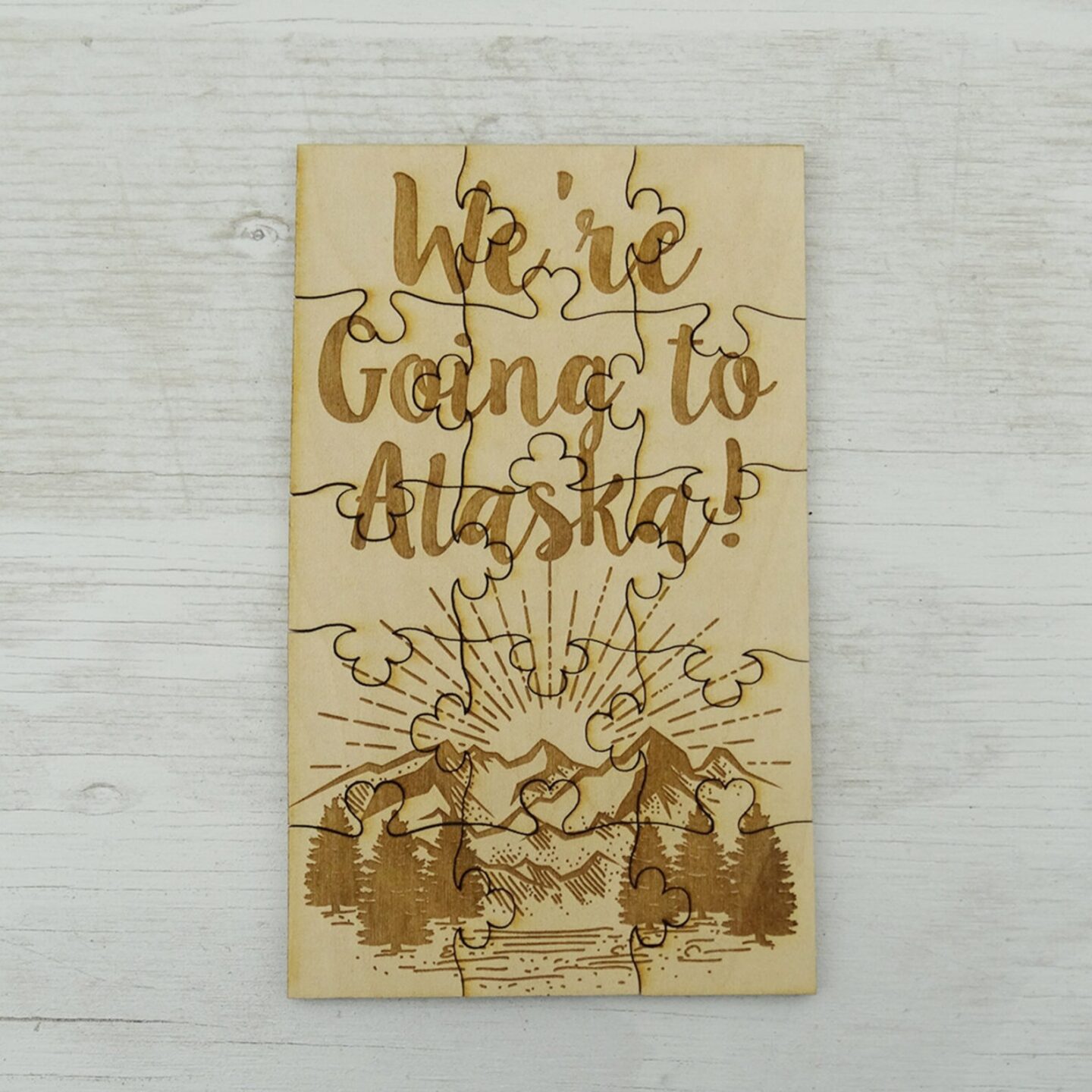 Wood puzzle that says "We're going to Alaska!" with the mountains on the bottom.