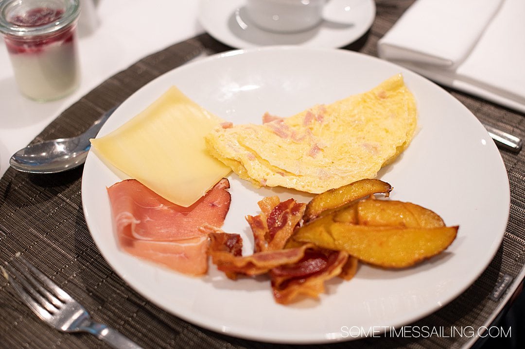 Plate of breakfast food on the Emerald Destiny river cruise ship with cheese, an omelette, potatoes, and meat.