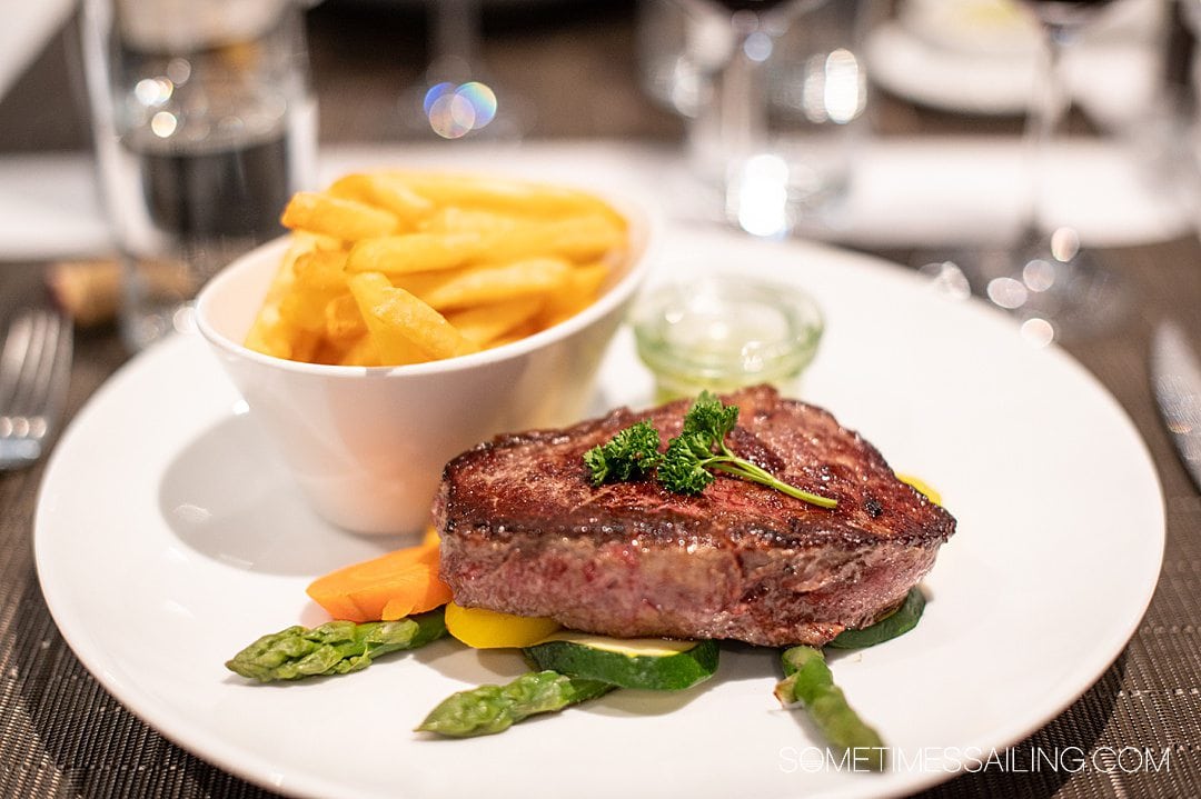 Emerald Destiny river cruise food: plate of sirloin steak filet on top of asparagus and carrots with a side of French fries.