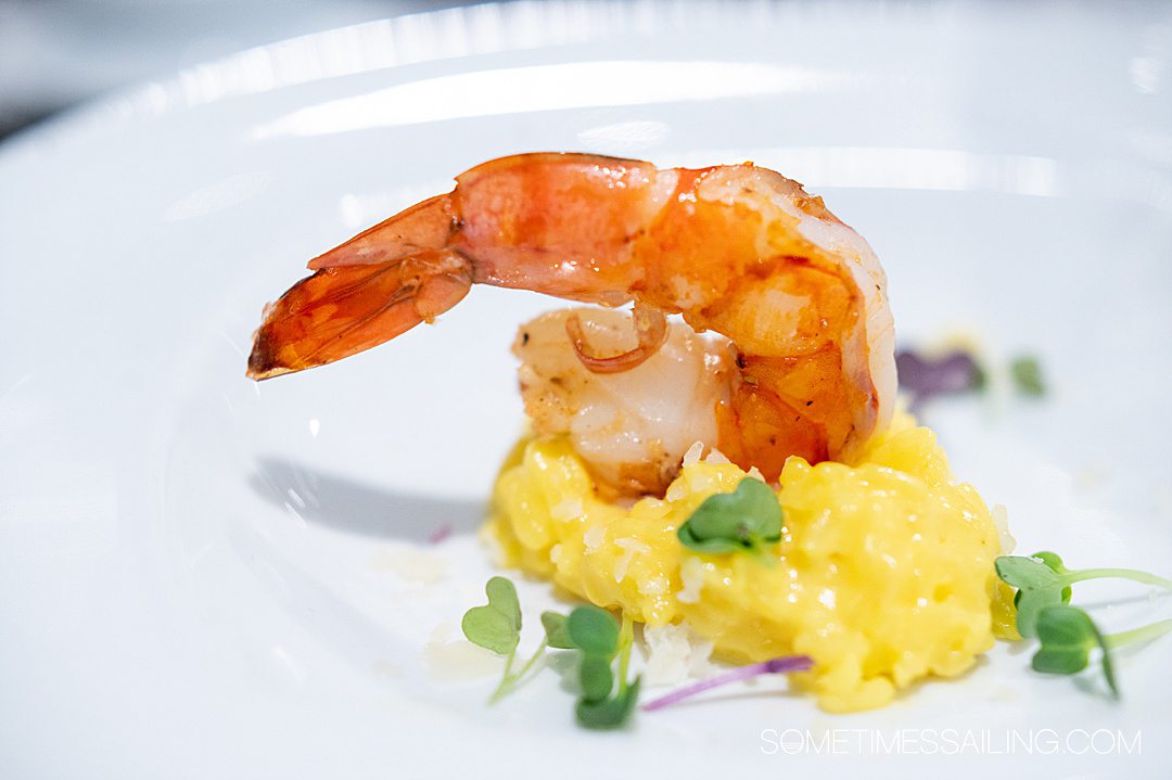 Yellow saffron rice with a large shrimp on top, and micro greens on the plate on an Emerald Destiny river cruise.