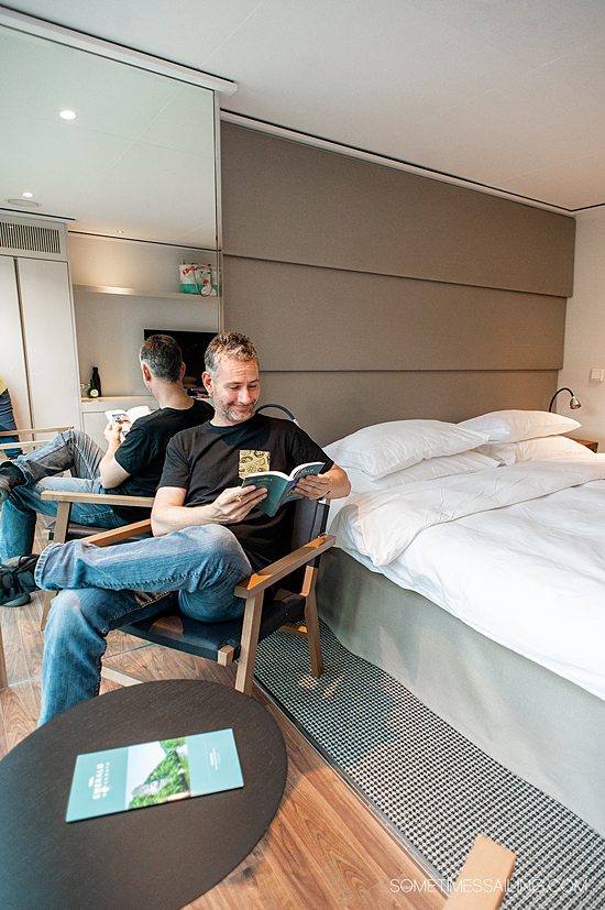 Man in a chair reading in a river cruise ship stateroom on Emerald Destiny.