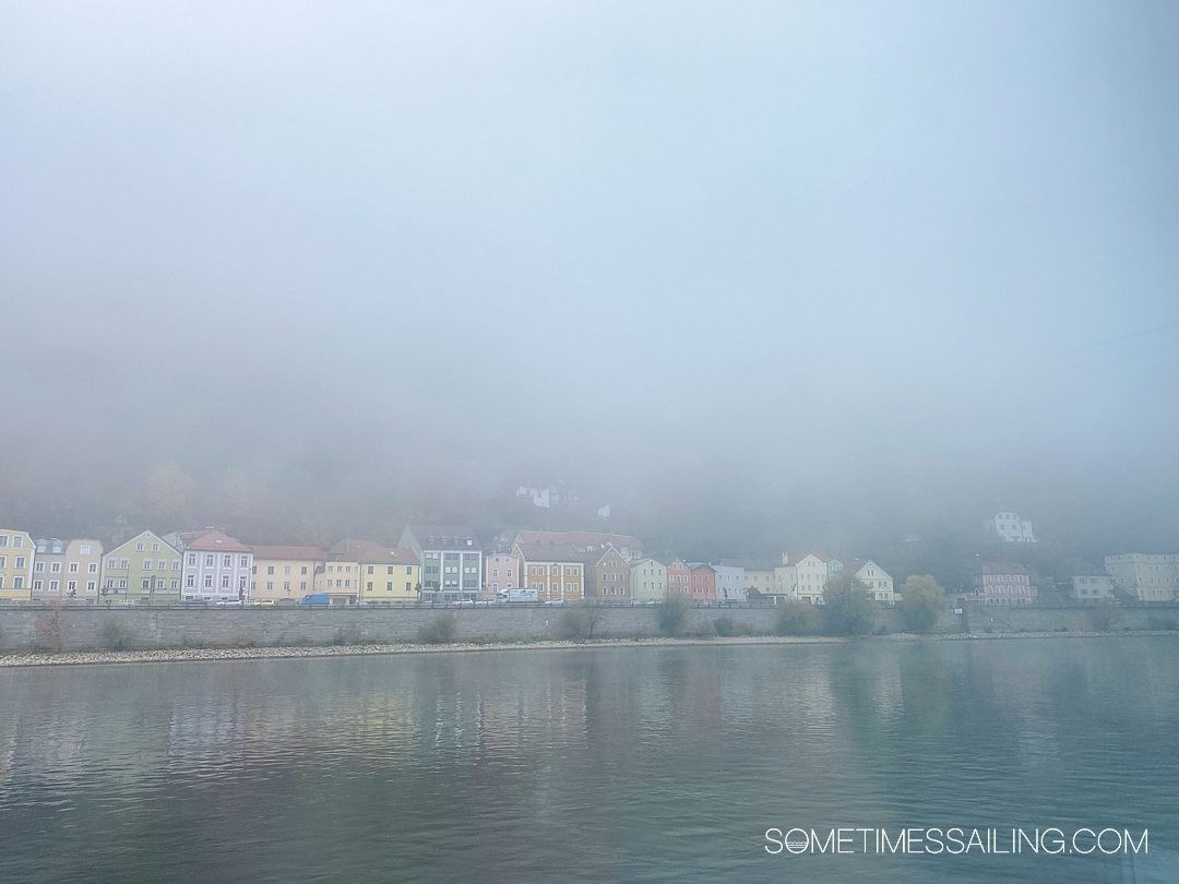Incredibly foggy view of the riverside on the Danube River in Passau, Germany, with colorful buildings in the distance.