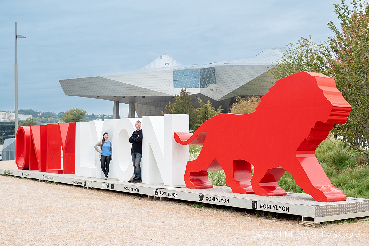 Man and a woman standing in the letters of a sign in Lyon, France.