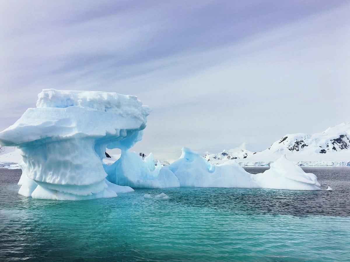 Purple and blue sky over the aqua blue water with a glacier in Antarctica.