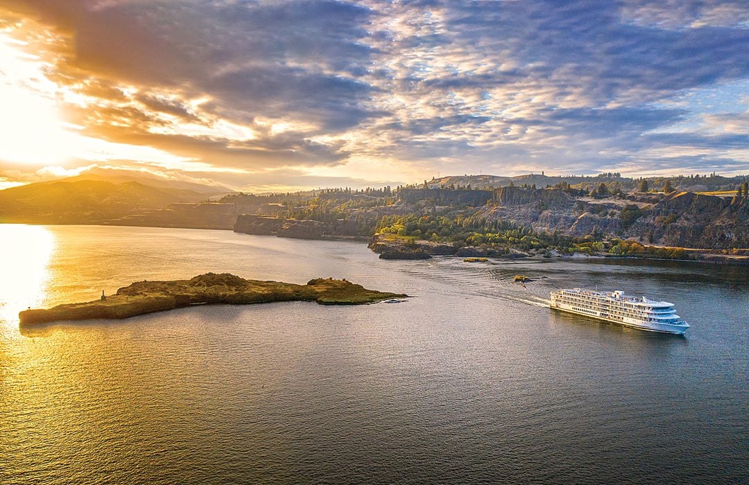 American Song aerial view of the America Cruise Lines river boat in the water on the west coast of the USA during golden hour sunset time.