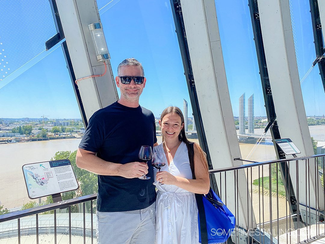 Couple toasting with two glasses of wine and the Garonne River behind them.