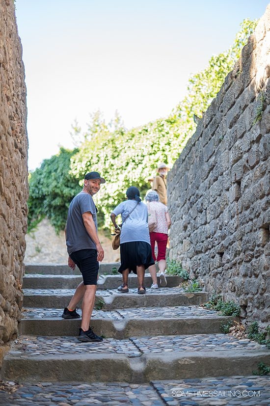 People walking up large stone medieval steps and a man looking back towards the camera.