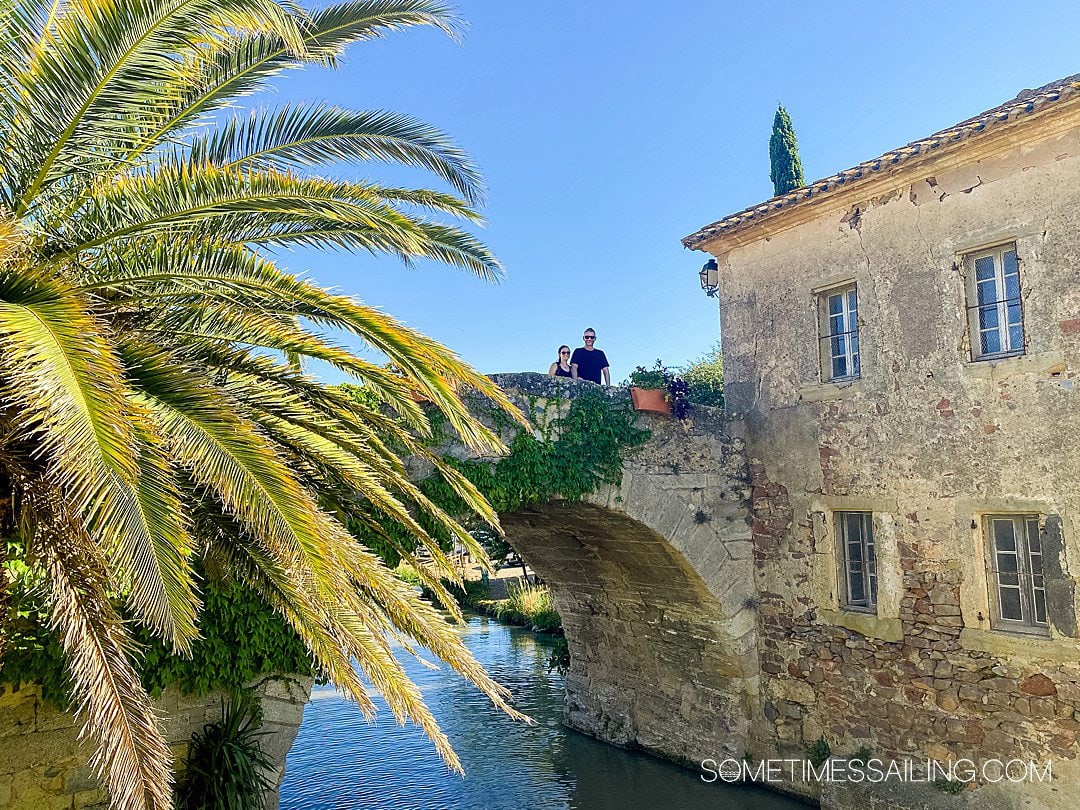 Couple on an old bridge in a small French town on a blue-sky day.