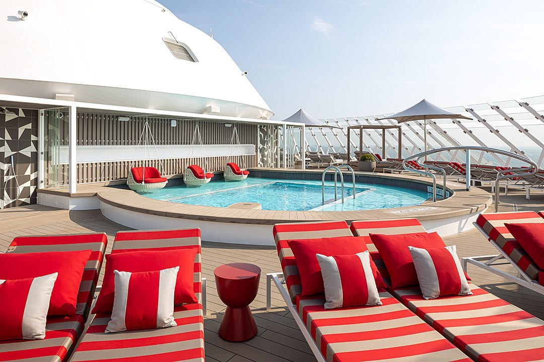 Red and white striped upholstry on lounge chairs outside The Retreat Sundeck pool on Celebrity Beyond.