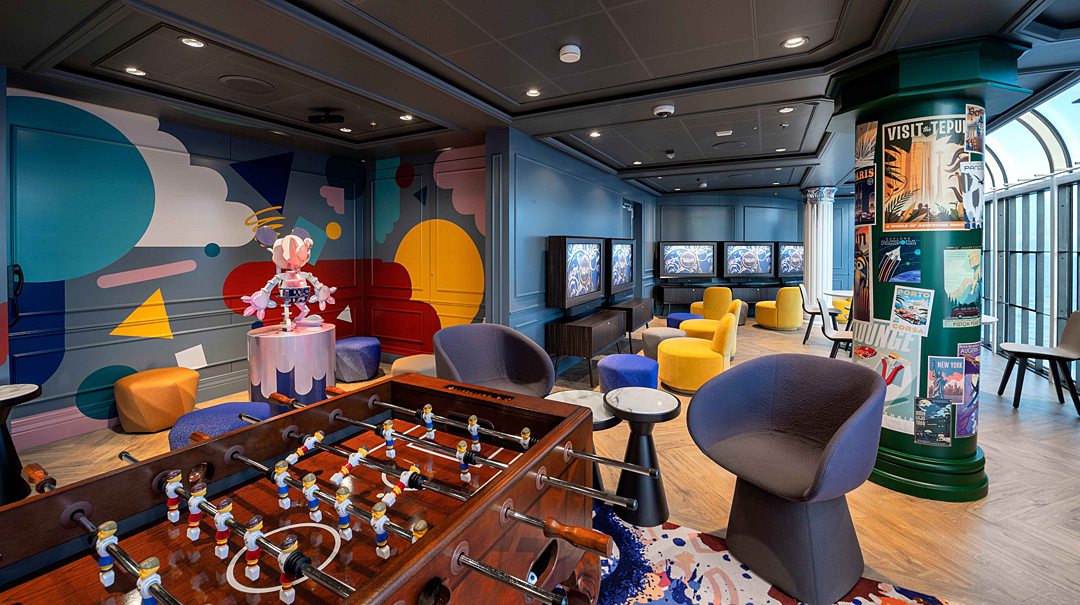 Inside of a cool teen lounge with striking solid color and a foosball table in the foreground.