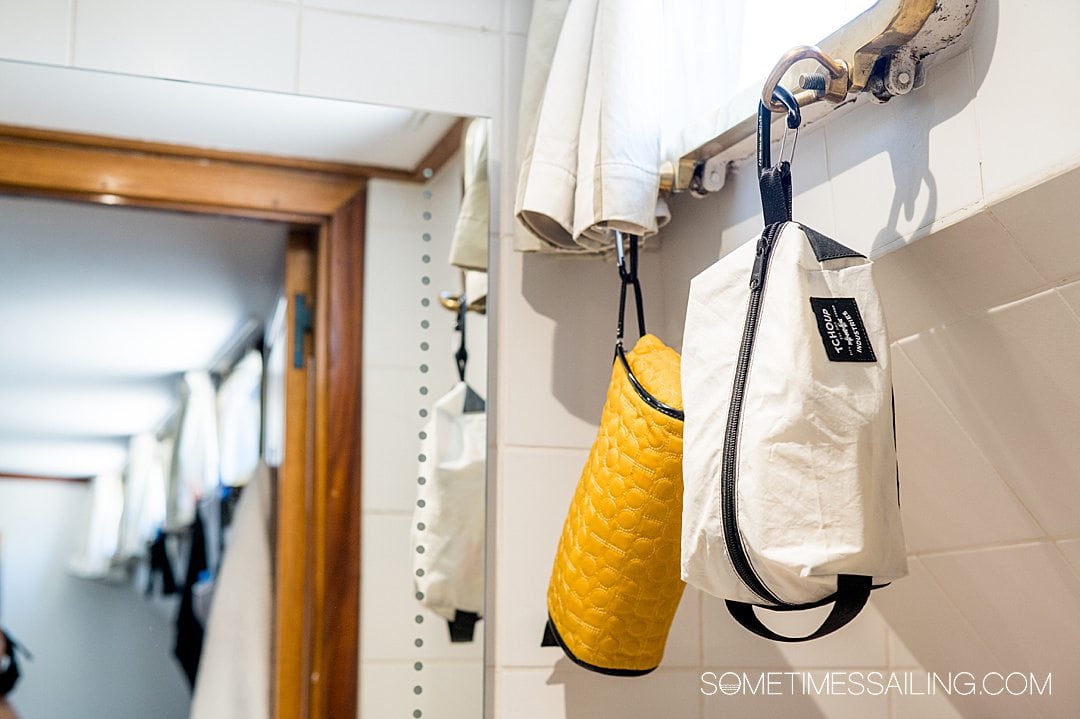 Toiletry bags hanging from a hook with carabiners in a cabin bathroom on a barge cruise ship.