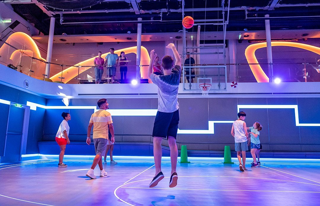 Kids playing indoor basketball with purple lighting on Disney Wish cruise ship.