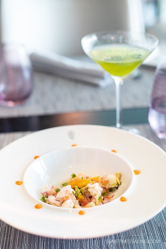 Bowl with a seafood dish and cocktail in a martini glass next to it at Luminae, a restaurant part of The Retreat on Celebrity Cruises.