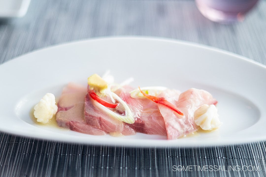 Appetizer plate with raw tuna slices and sliced vegetables on top at Luminae in The Retreat, part of Celebrity Cruises.