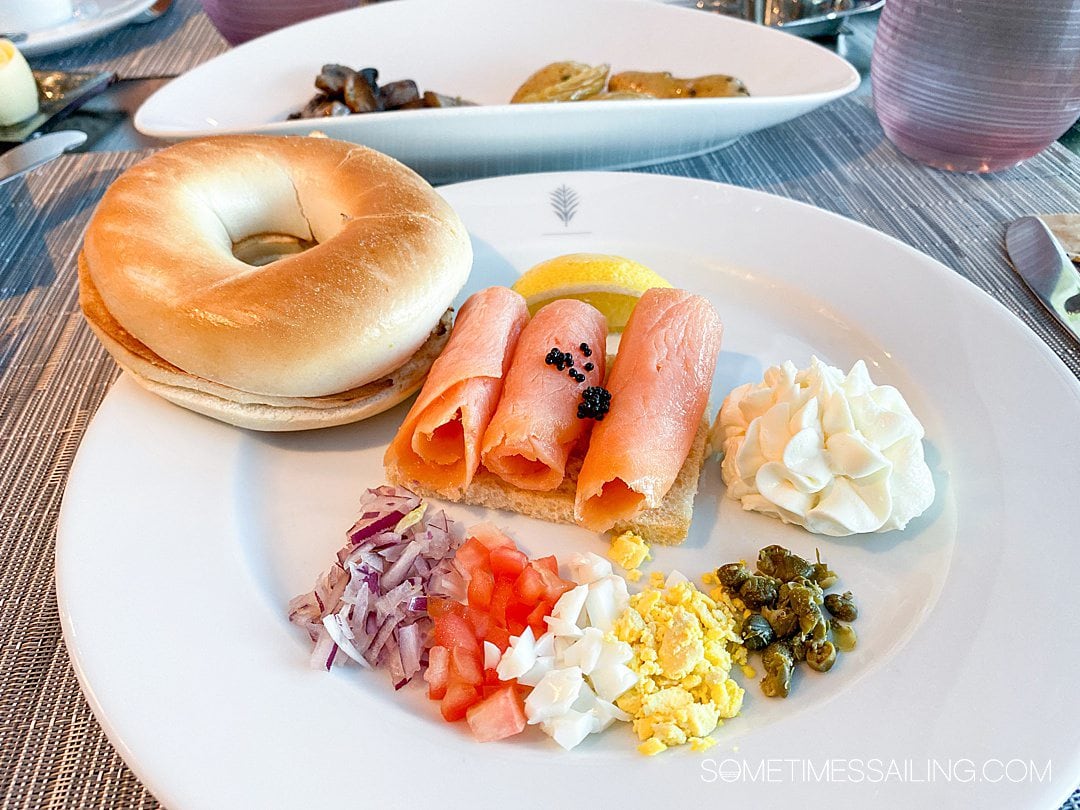 Breakfast plate of three rolls of smoked salmon and toppings onion, tomato, egg and capers and a side bagel at Luminae on Celebrity Cruises.