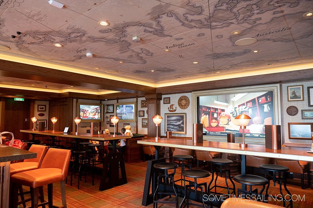 Disney Wish cruise ship details: inside Keg and Compass bar with a map on the ceiling and dark wood finishes.
