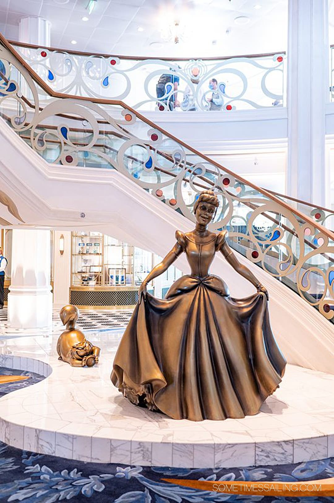 Bronze Cinderella statue with Lucifer the cat behind her on Disney Wish cruise ship in the Grand Hall.