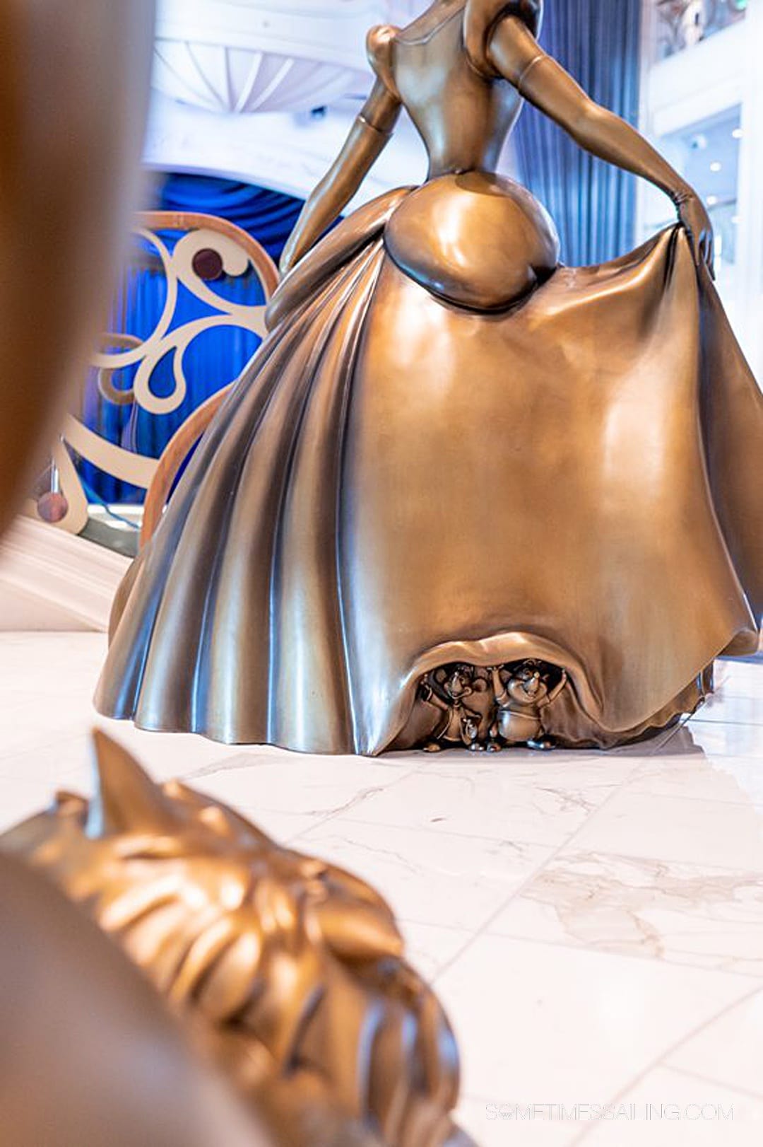 Bronze Gus and Jacque mice peeking out from Cinderella's gown on Disney Wish cruise ship in the Grand Hall.