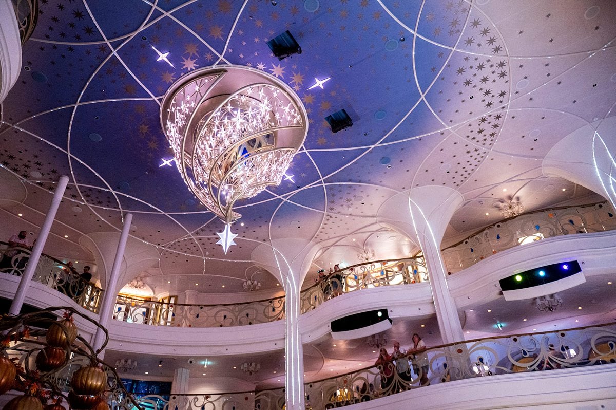 Ceiling of the Grand Hall. The Disney Wish details are apparent in the Cinderella-inspired chandelier, wishing stars and twinkling lights that span 3 decks.