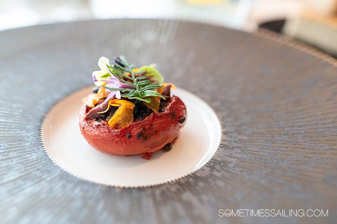 Tomato dish with flowers and a fern on top, on Disney Wish restaurant Enchante.