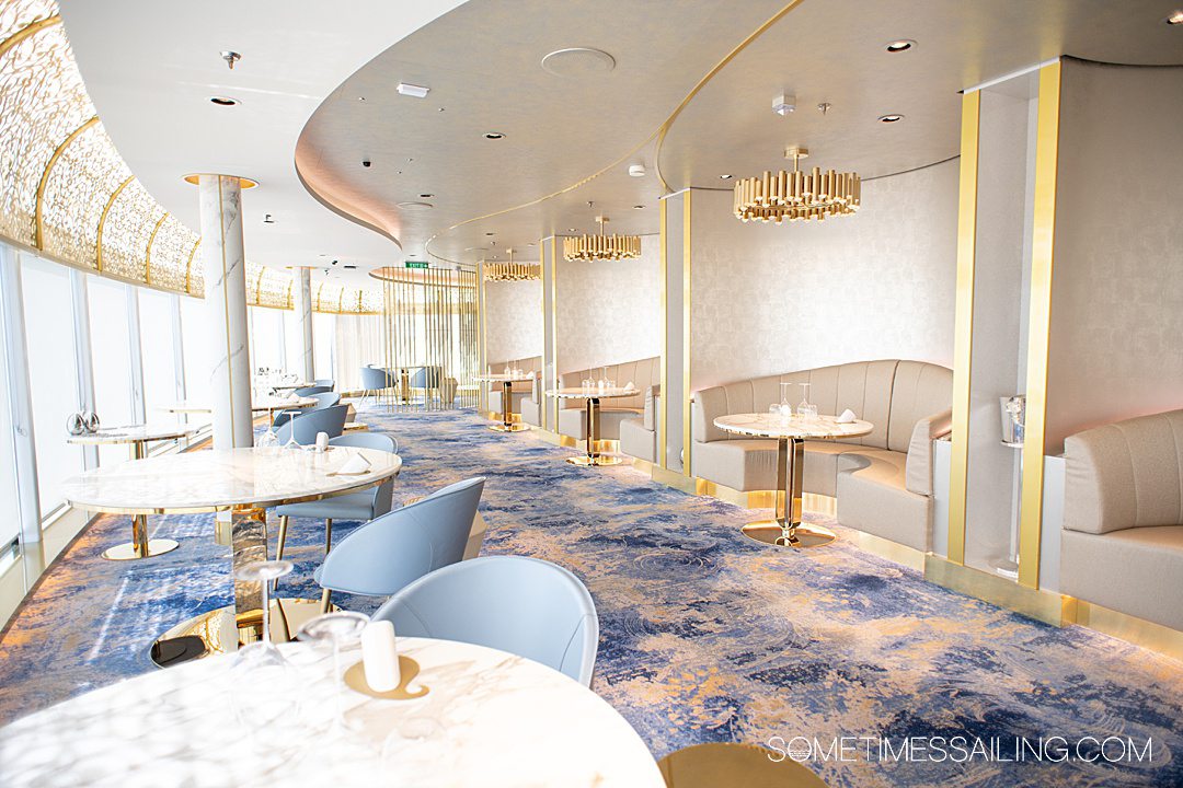 White and gold interior of Enchante restaurant on Disney Wish cruise ship with blue patterned carpet.