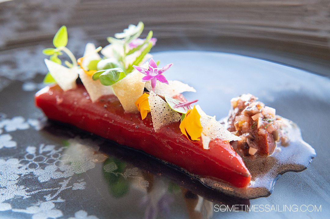 Entree plate with a pink-colored wedge of a pie, covered with flowers and crisp triangles at Enchante on Disney Wish cruise ship.