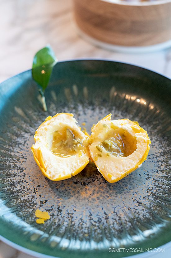 Teal round plate with a yellow lemon dessert cut in half at Disney Wish's Enchante adult-only restaurant.