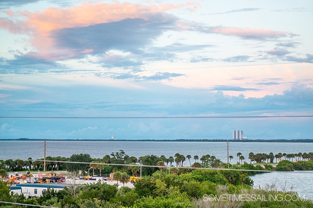 Beautiful orange, blue and pink sunset with trees in the foreground and shuttle launches in the distance near Port Canaveral.