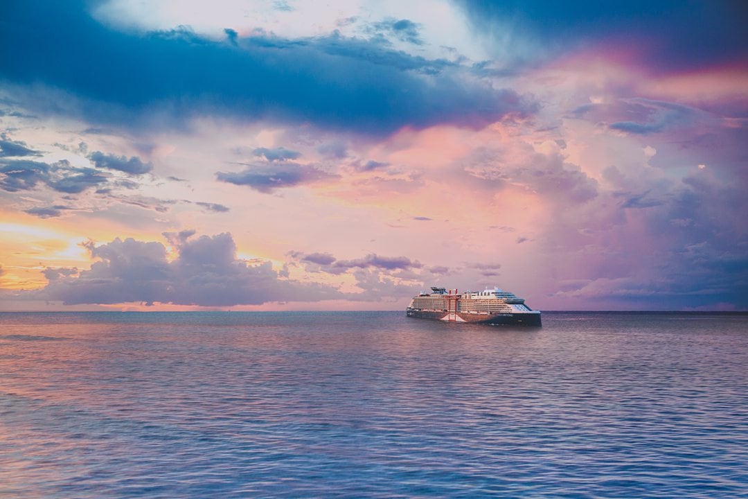 Pink, purple and blue sunset over the ocean with the Celebrity Beyond ship in the distance.