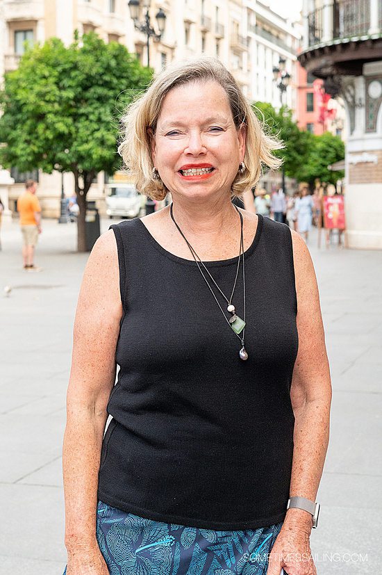 Woman with short blond hair wearing a black tank top, in a street in Seville.