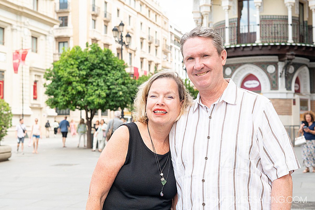 Man and a women standing in front of a building with the woman leaning her head on the man.