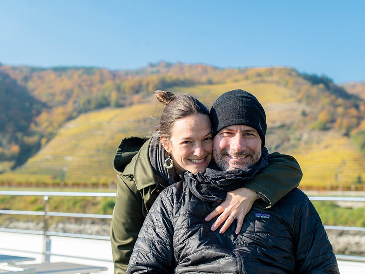 Couple with the Wachau Valley behind them on the Danube River with Emerald Cruises.